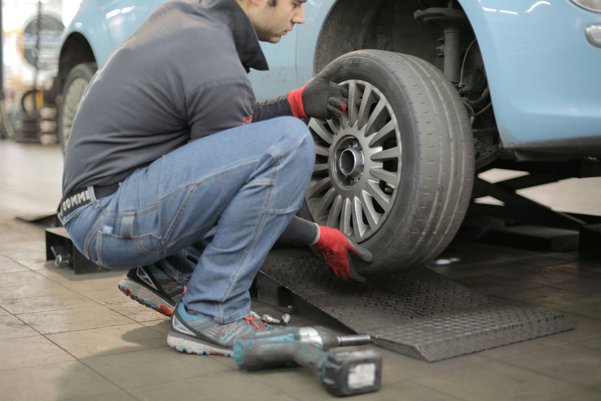 Mechaniker wechselt einen Autoreifen im Haus und verwendet dabei Werkzeuge zur Fahrzeugwartung.