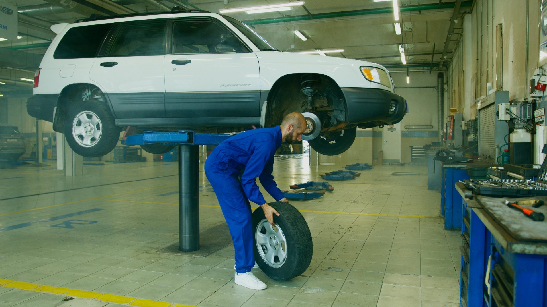 Mechaniker ersetzt in einer professionellen Autowerkstatt einen Reifen an einem höhergelegten SUV.
