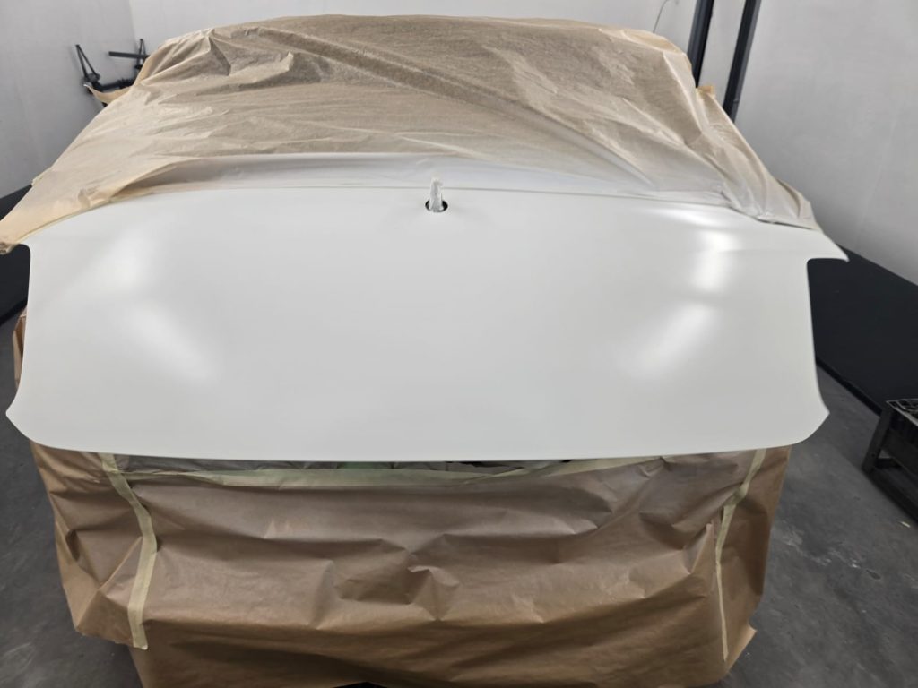Frisch lackierte Motorhaube in Weiß, matt getrocknet, abgeklebt zum Schutz vor Overspray.
